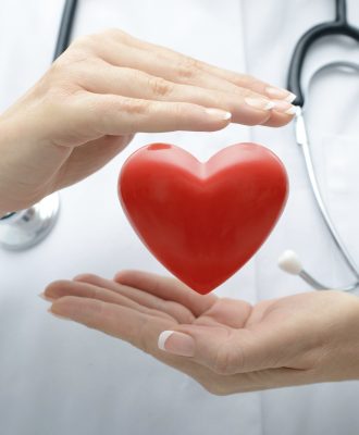 Female doctor with the stethoscope holding heart